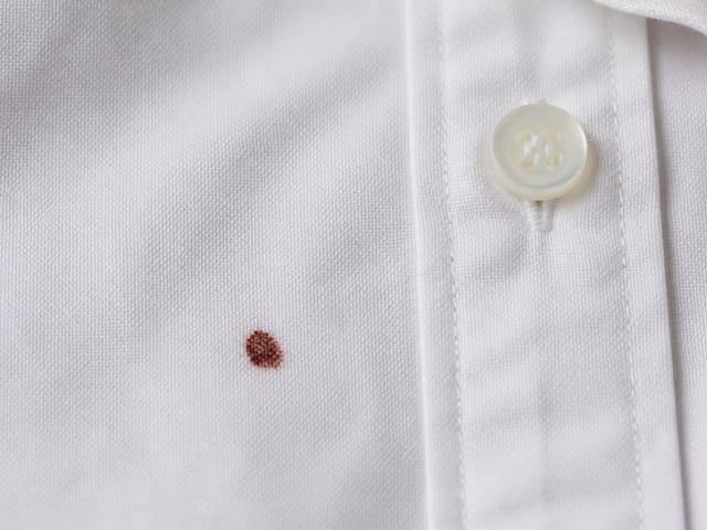 Pequeña mancha de sangre seca en una camisa blanca