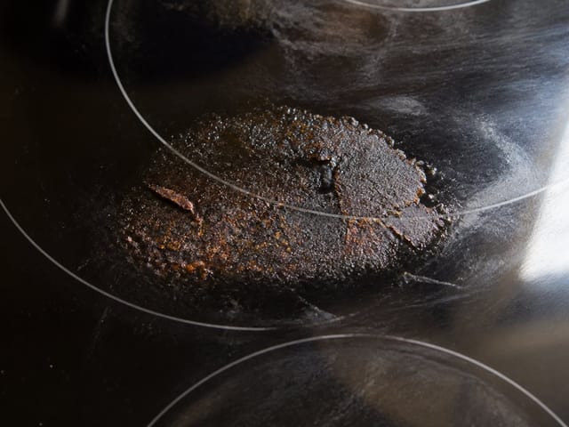 Résidus d'aliments brûlés sur une table de cuisson en verre
