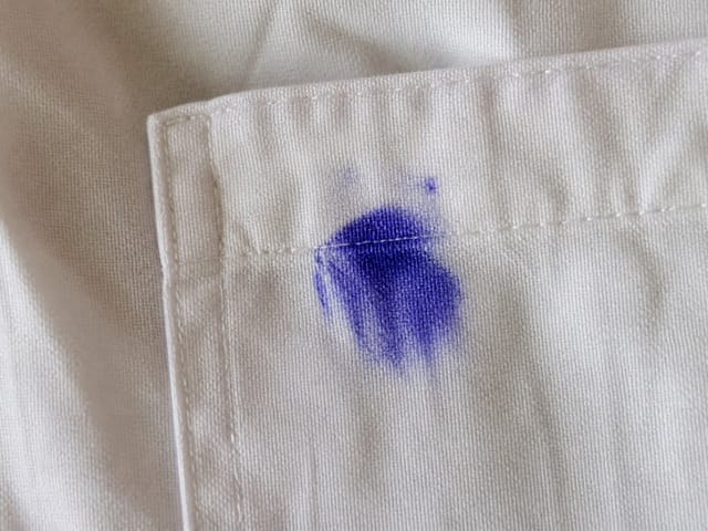 Mancha de tinta en el bolsillo de una camisa blanca
