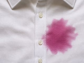 Tache de vin rouge violacé sur la patte de boutonnage d'une chemise habillée blanche